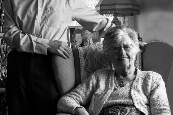 Older couple in their front room with a photo of how they looked years ago